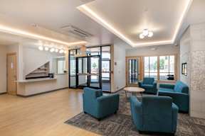 A spacious waiting area with blue chairs and a reception desk.