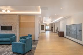 A hallway with blue chairs and a fireplace.
