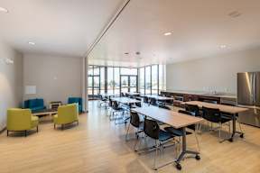 A room with tables and chairs and a kitchen area.