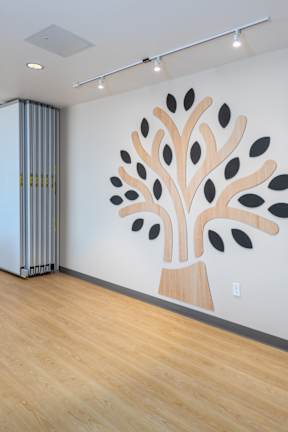 A tree mural on a wall in a room with wooden floors and a white wall.