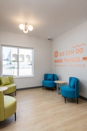 A room with a quote on the wall and two chairs.