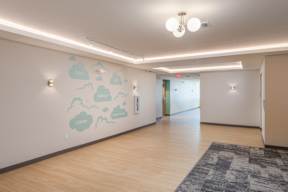 A hallway with a wall mural of clouds and the words "great", "challenge", "learn", and "imagine" written on it.