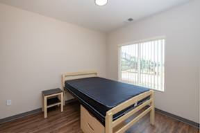 A bedroom with a bed, chair, and window.