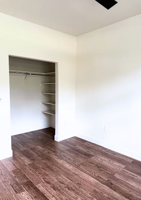 A room with a brown floor and a white wall with a doorway.