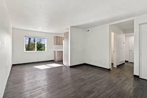 A large empty room with faux wood floors and white walls at Gateway Village Apartments in Fort Morgan, CO, 80701