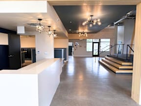 A spacious interior with a white reception desk and a staircase with black railings.