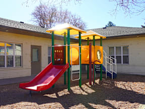 A playground with a red slide and a yellow and green structure at Mountain Terrace Apartments, Westminster, CO.