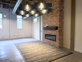 A room with a brick fireplace and a television mounted above it.