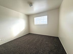 A room with a window and carpeted floor at Townview Plaza Apartments, Denver, CO.