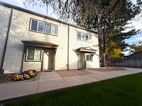 A beige house with a flower bed in front.