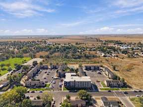 A large building complex with a parking lot in front of it at Gateway Village Apartments in Fort Morgan, CO, 80701