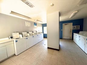 A laundry room with washers and dryers lined up at Grand Manor Apartments, Colorado.