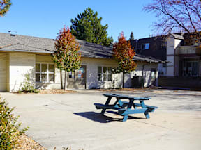 A blue picnic table is in front of a yellow building at Mountain Terrace Apartments, Westminster, Colorado.