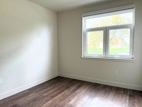 A room with a window and wooden flooring.
