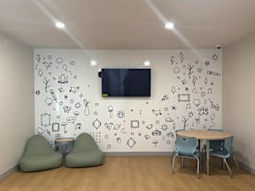 A room with a white wall decorated with drawings and a table with four chairs.