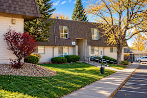A small building with a grey roof and a white door is surrounded by trees and grass t Mountain Terrace Apartments , Westminster, CO, 80031