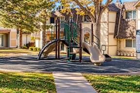 A playground with a slide and a green fence t Mountain Terrace Apartments , Westminster, CO, 80031