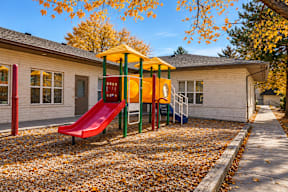 A playground with a red slide and a yellow canopy t Mountain Terrace Apartments , Westminster, CO, 80031