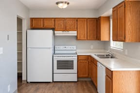 A kitchen with wooden cabinets and white appliances t Mountain Terrace Apartments , Westminster, CO, 80031