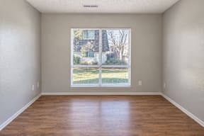 A room with wooden floors and a large window showing a view of a house t Mountain Terrace Apartments , Westminster, CO, 80031