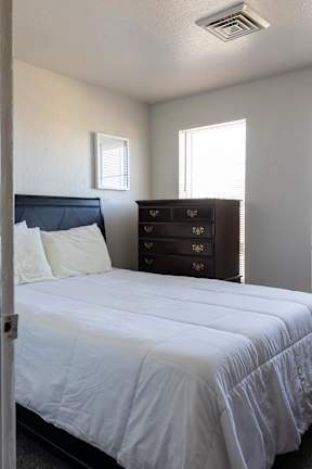 A bedroom with a bed, dresser, and window at Meeker Commons, Greeley, CO, 80631