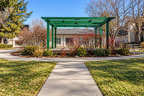 A green pergola is situated in the middle of a grassy area with a concrete walkway leading to it  t Mountain Terrace Apartments , Westminster, CO, 80031