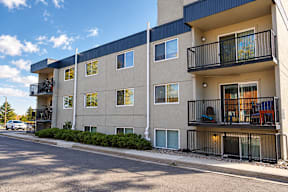 A modern apartment building with balconies and a blue awning.