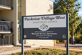 A sign for Parkview Village West Apartment Homes stands in front of a building.