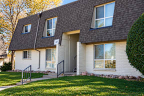 A white house with a grey roof and a black gate t Mountain Terrace Apartments , Westminster, CO, 80031