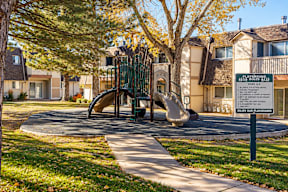 A playground with a slide and a sign in front of a building t Mountain Terrace Apartments , Westminster, CO, 80031