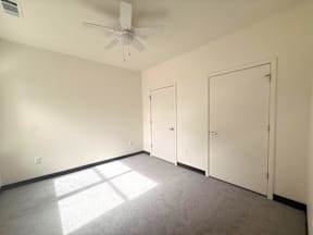 A room with a ceiling fan and three doors.