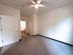 A room with a ceiling fan and carpeted floor.