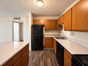 A kitchen with a black fridge and wooden cabinets.