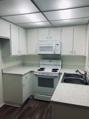 A kitchen with white cabinets and a white microwave above the stove.