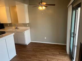 A kitchen with white cabinets and a ceiling fan.