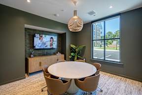 A conference room with a large table, chairs, and a television on the wall.