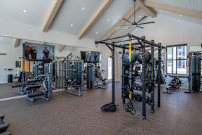 A gym with a variety of equipment including a weight bench, a leg press machine, a cable machine, a squat rack, a rowing machine, a treadmill, a stationary bike, a kettlebell