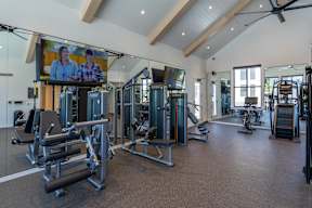 A gym with a television screen showing two people talking.