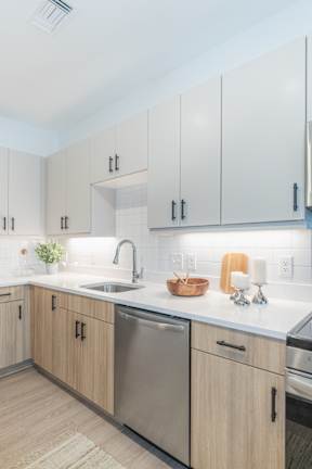 A kitchen with wooden cabinets and a stainless steel dishwasher.