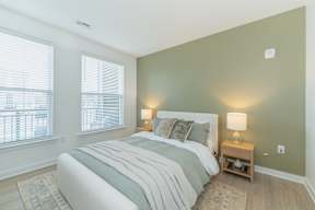 A bedroom with a large bed and two lamps.
