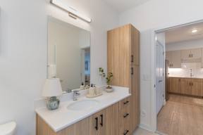 A bathroom with a sink, mirror, and wooden cabinets.