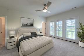 A bedroom with a large bed, a ceiling fan, and a picture on the wall.