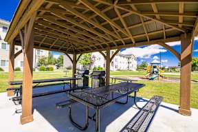 A wooden pavilion with a black table and benches.