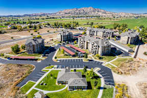 A large, modern building complex with a parking lot in front.