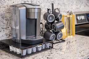 A coffee machine and a set of mugs are on a counter.