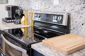 A modern kitchen with a black stove top oven and a wooden cutting board.