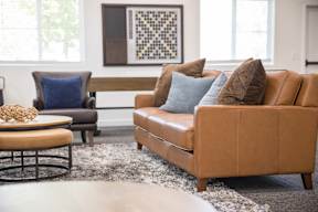 A living room with a brown couch and a blue pillow.
