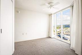a bedroom with a large window and a ceiling fan
