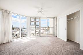 a bedroom with a large window and a ceiling fan