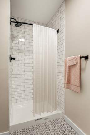 a bathroom with white subway tiles and a shower and a pink towel